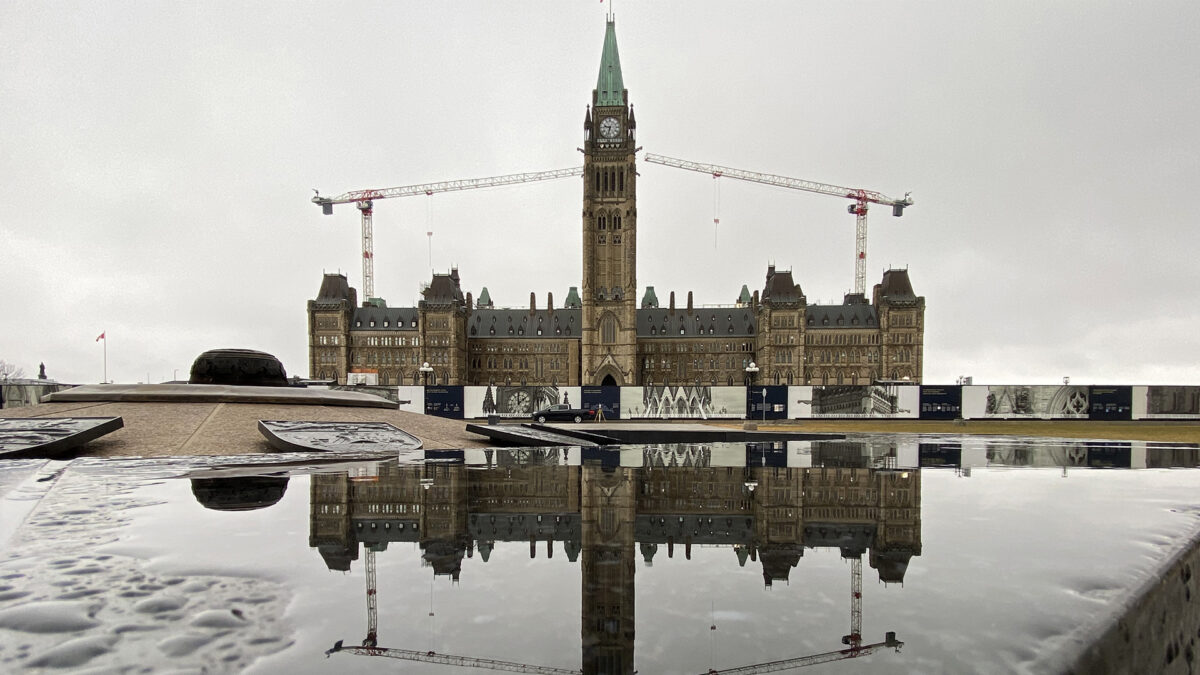 A rainy day view of Ottawa's parliament buildings, surrounded by barriers for construction.